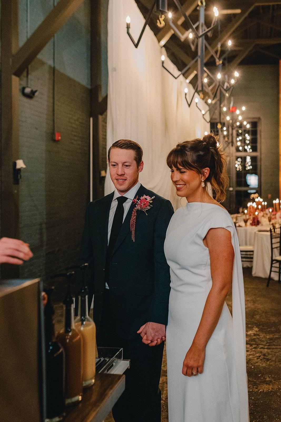 Newlyweds at the coffee bar in a candlelit reception hall