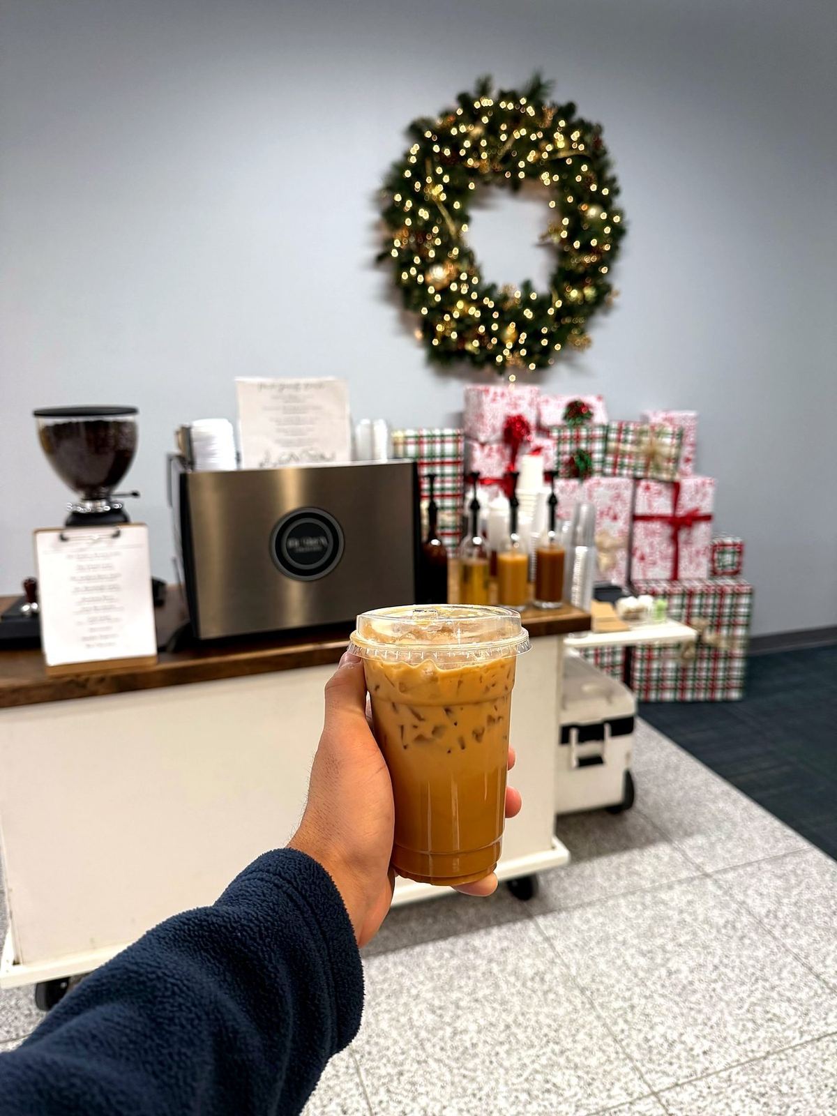 Iced coffee at a holiday office pop-up with wreath and gifts
