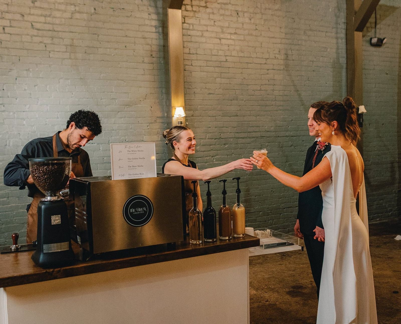 Brew Collective baristas handing a latte to a bride and groom at their reception