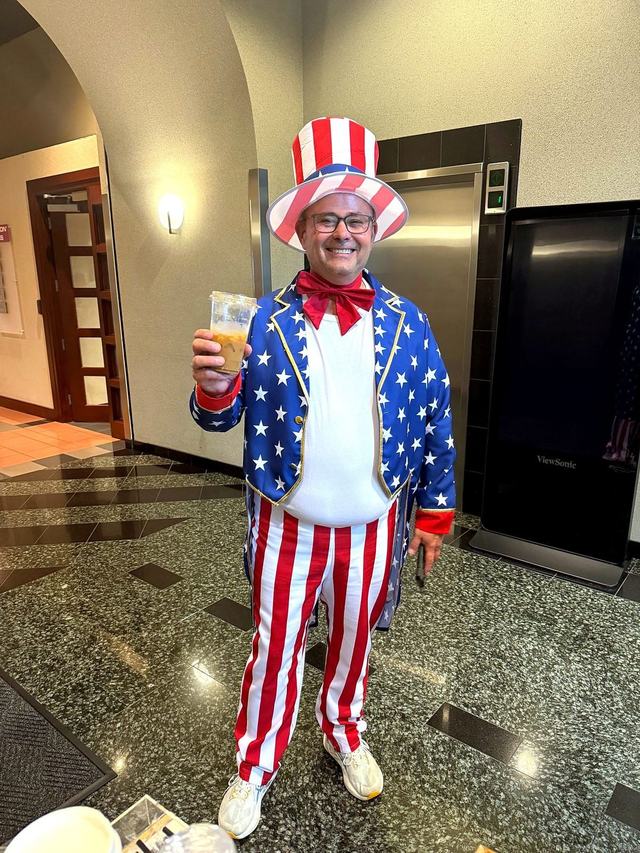Office guest in a Fourth of July costume raising an iced coffee